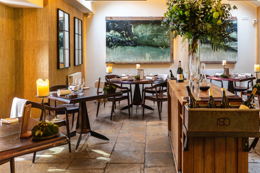 The dining room at Sat Bains in Nottingham, with wooden tables and a large painting on the wall